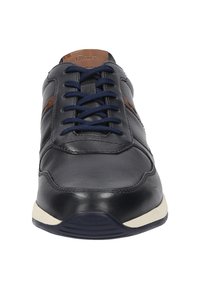 Marine leren sneaker met donkerblauwe veters, bruine accenten en een crèmekleurige rubberen zool, met een ronde neus en een gladde textuur.