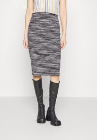 Černobíle pruhovaná, sukne do délky kolen v střihu tužky, vyrobená z elastické látky, doplněná vysokými černými botami s bočním zipem.