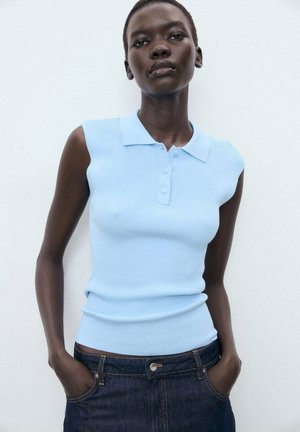 Light blue sleeveless polo top with ribbed texture, featuring a collar and three-button placket, paired with dark denim jeans.