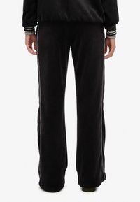 Zwarte corduroy sweatpants met een wijd beenontwerp, voorzien van witte zijstrepen en een gestructureerde oppervlakte.