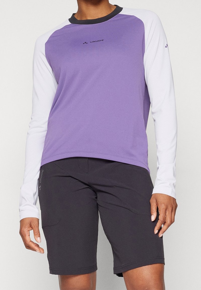 Lätt lila och vit långärmad tröja med svart krage, i kombination med svarta shorts. Har logotypdetalj på framsidan.