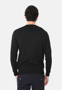 Maglione nero a maglia con scollatura rotonda, maniche lunghe e polsini a coste. Presenta una texture liscia e una silhouette aderente.