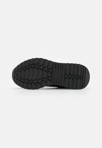 Suola di scarpa in gomma nera con un motivo di battistrada frastagliato per una migliore aderenza, con un tacco liscio e arrotondato e scanalature superficiali per una maggiore flessibilità.