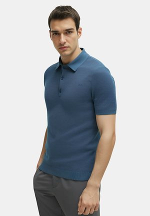 Polo a maniche corte di un profondo blu. Presenta un colletto, chiusura a tre bottoni, tessuto texturizzato e orlo a coste.