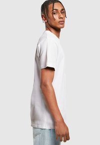 Hvid bomulds t-shirt med korte ærmer, klassisk crew neck design, glat tekstur og en afslappet pasform, parret med lyseblå jeans.