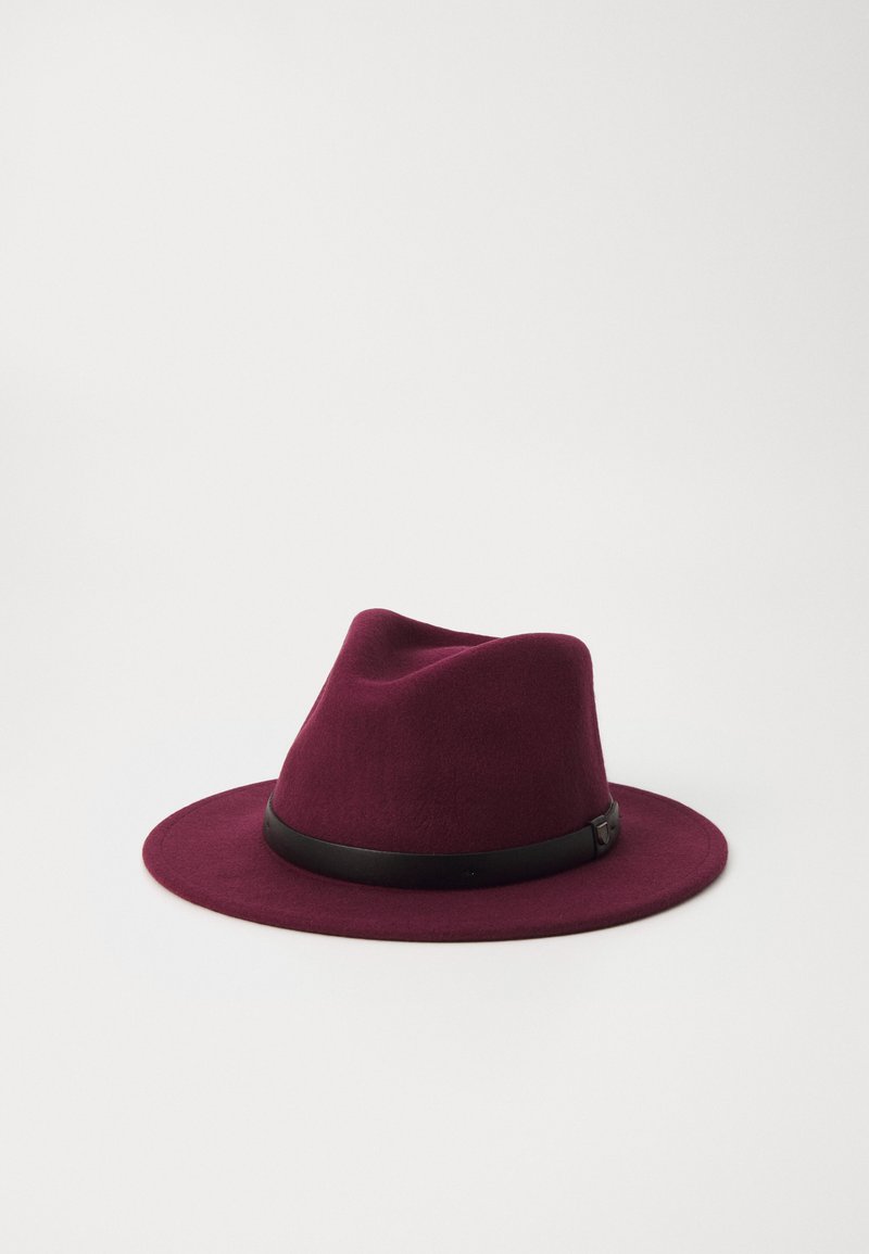 Chapeau fedora en feutre bordeaux avec un large rebord et une bande en cuir noir autour de la base, présentant une texture lisse et un design structuré.
