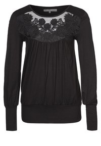 Svart långärmad överdel med ett strukturerat blommönstrat spetsfält över bröstet, samlad tyg under bysten och åtsittande ärmslut.