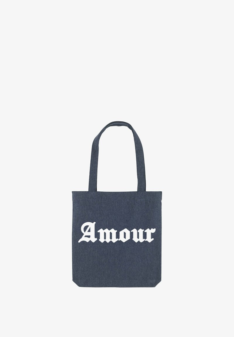 Sac en denim avec deux poignées, arborant le texte blanc "Amour" dans une police décorative, de forme rectangulaire et en tissu texturé.