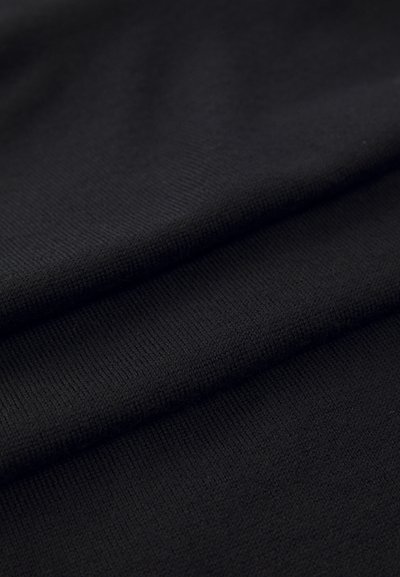 Melnā adīta auduma ar gludu tekstūru, ar smalkām ribu struktūrām un vienmērīgu krāsu vairāku slāņu garumā.