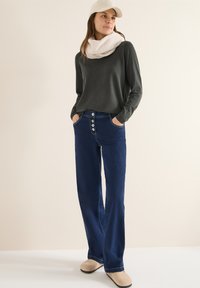 Ciemnoszara koszula z długim rękawem, jasnobeżowy szalik, niebieskie, wysokowzsitowe dżinsy z guzikami oraz beżowe buty. Prosty design i luźny krój.