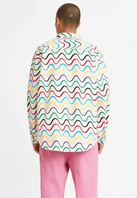 Camisa de manga larga en tela ligera con un patrón ondulado multicolor sobre fondo blanco, con dobladillo curvado y puño abotonado.