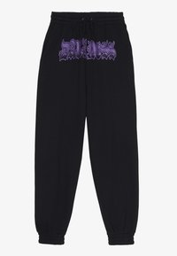 Svarta sweatpants med elastisk midja och manschetter, med lila grafisk text "DRAIN" framtill. Mjukt tyg med lös passform.