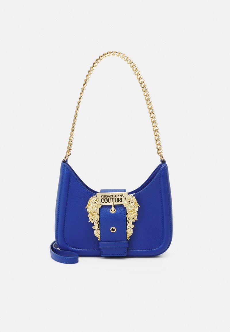Sac à main en cuir bleu avec une silhouette courbe, une quincaillerie lion dorée et une bandoulière chaîne. Présente un logo proéminent et une finition texturée.