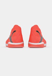 Jasnoróżowe sportowe buty mają górę wykonaną z eleganckiego tekstylnego materiału, białą środkową podeszwę oraz czarne akcenty po bokach, które podkreślają detale wzornicze.