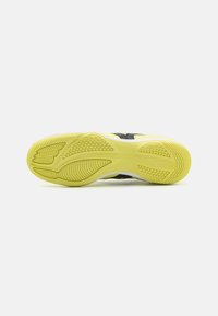 Suela de zapatilla de correr negra con una entresuela de goma amarilla, patrones de agarre texturizados y ranuras de flexión para una mejor tracción y flexibilidad.