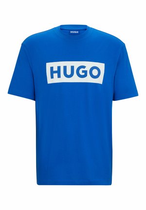 Blå bomull T-skjorte med en stor hvit rektangulær grafikk med teksten "HUGO" i fete blå bokstaver. Klassisk rund hals og korte ermer.