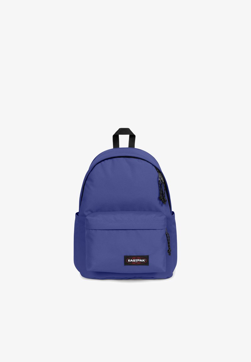 Lila nylonryggsäck med rundad topp, framficka med dragkedja och svart logotypmärke. Har svarta dragkedjeöglor och ett robust handtag på toppen.