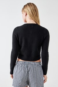 Musta lyhyt villapaita, jossa on pitkät hihat, neulepinta ja resorihäntä, yhdistettynä ruudullisiin shortseihin, nähtynä takakautta.