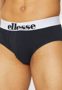Fekete pamut alsónadrág fehér elasztikus derékkal, amelyen fekete "ellesse" logó található. Simább textúra, elülső zsebszerkezet, testhezálló fazon.