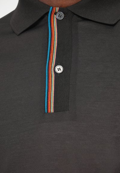 Μαύρο πουκάμισο πόλο με υφή, με κουμπί στο μπροστινό μέρος διακοσμημένο με πολυχρωμία ρίγα κατά μήκος του γιακά.