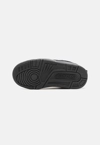 Semelle de sneaker en caoutchouc noir présentant des motifs de relief détaillés, des accents circulaires et un logo "JORDAN" en relief sur le côté.