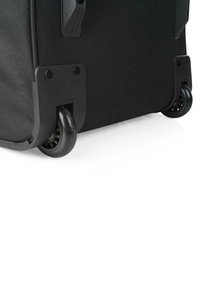 Esquina de maleta negra con tela duradera, acentos de plástico resistente y ruedas suaves para una fácil movilidad.