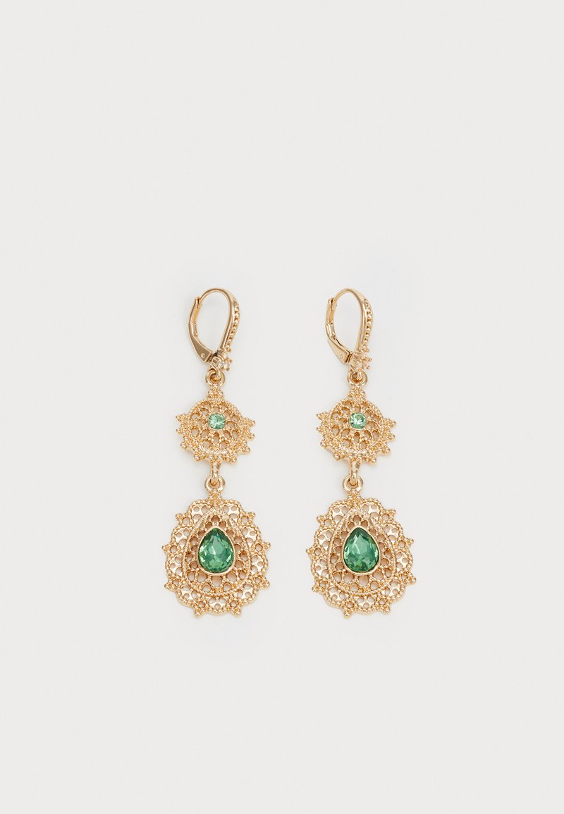 Pendientes en tono dorado con un intrincado diseño de encaje, que presentan dos piedras preciosas verdes en forma de gota, suspendidas de un pequeño acento circular.