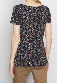 Short-sleeve top in dark navy fabric featuring a colorful floral pattern with red, yellow, blue, and white accents. Round neckline.
