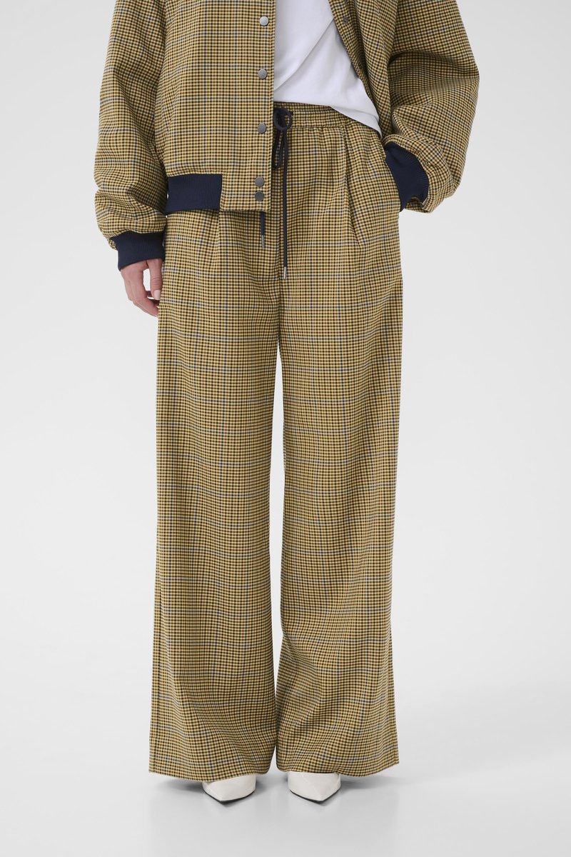 Checkered yellow and black pants with a loose fit, featuring an elastic waistband and side pockets, paired with a matching checkered jacket.