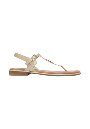 Sandale plate beige avec bride cheville, boucle dorée, design à bride en T et petit talon empilé sur fond blanc.