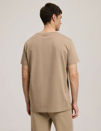 Beżowa bawełniana koszulka z klasycznym okrągłym dekoltem i krótkimi rękawami. Posiada luźny krój i gładką fakturę. Z tyłu brak logo.