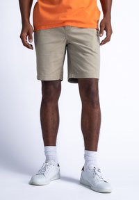 Khaki shorts met een rechte snit, gemaakt van katoenmix stof, gecombineerd met witte sneakers en witte kousen tot aan de enkel.