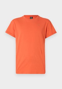 Kortermet oransje T-skjorte i lett stoff med rund hals og liten logodetalj øverst til venstre.