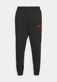 Pantalon de survêtement noir Adidas avec taille et poignets élastiques, avec un petit logo rouge Adidas sur la partie supérieure de la cuisse gauche.
