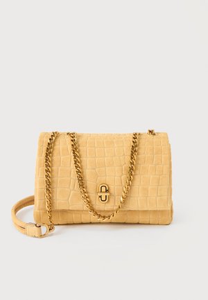 Κίτρινη τσάντα ώμου από δέρμα με υφή, με χρυσή αλυσίδα ιμάντα και κούμπωμα, ορθογώνιο σχήμα, ακουμπισμένη σε ανοιχτό φόντο.