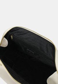 Borsa in pelle bianca con zipper dorato, con interno nero e tasca con zip. Il tessuto interno presenta un motivo a logo ripetuto di Armani Exchange.