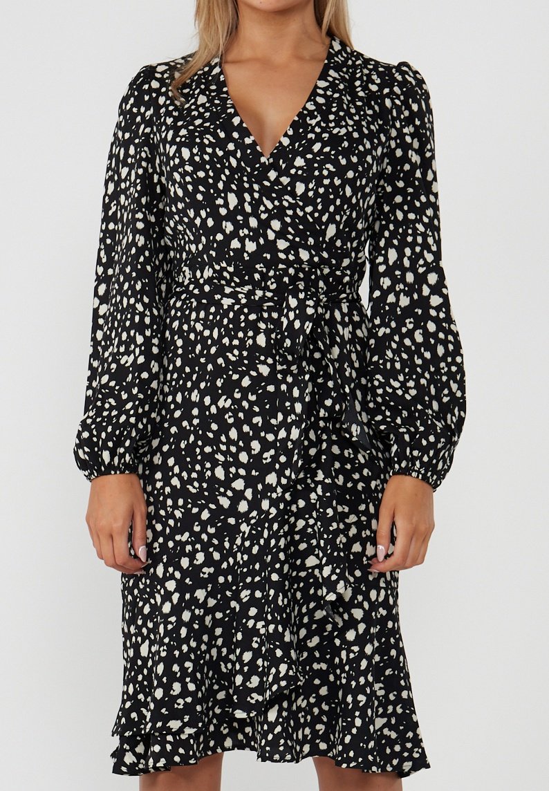 Black wrap dress with a white speckled pattern, long puffed sleeves, and a tie waist. Textured fabric and ruffled hem detail.