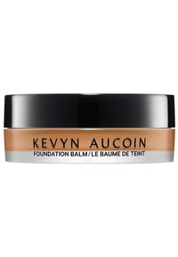 Baume de la fondation Kevyn Aucoin dans un conteneur rond avec un couvercle noir, produit crémeux beige visible, texte étiqueté sur le devant.