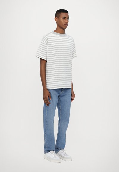 Striped t-shirt in light gray and white, made from a soft fabric, paired with light blue straight-leg jeans and white sneakers.