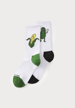 White socks with green and black accents. One sock features a yellow corn graphic; the other displays a green pickle character waving.