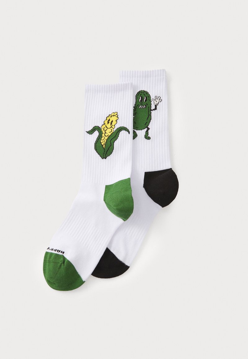 Baltas zeķes ar zaļiem un melniem akcentiem. Viena zeķe ir ar dzeltena kukurūzas grafiku; otra rāda zaļu gurķa tēlu, kas māj.