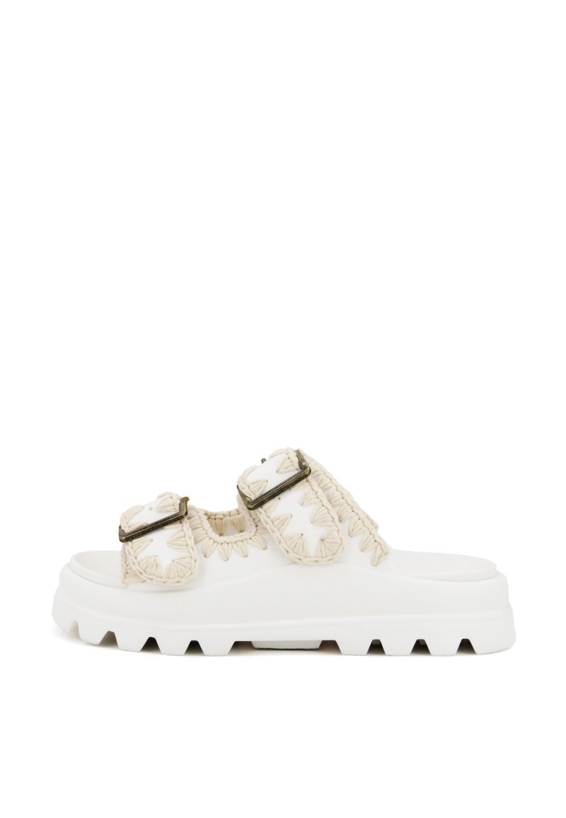 Sandali platform bianchi con doppie cinghie intrecciate e fibbie metalliche, lati texture e suola spessa con bordo seghettato.