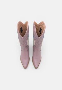 Jasnofioletowe skórzane kowbojki z wydłużonymi czubkami, misternym przeszyciem oraz kontrastującymi kremowymi i niebieskimi akcentami. Klasyczny styl zachodnioamerykański.