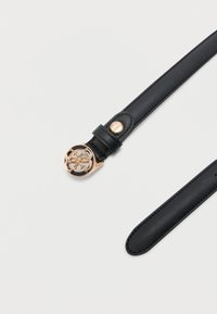 Μαύρη δερμάτινη ζώνη με στρογγυλή χρυσή αγκράφα που διαθέτει διακοσμητικό σχέδιο διαπλοκής και ένα μικρό χρυσό κουμπί με το λογότυπο κοντά στην αγκράφα.