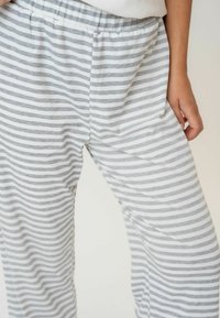 Prugaste hlače napravljene od mekog, prozračnog materijala, s izmjeničnim svijetlo sivoj i bijelim prugama. Pojas je elastičan za dodatnu udobnost.