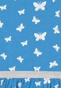 Blått tyg med vita fjärils mönster. Volangkant med ett silverfärgat elastiskt band. Slät textur över hela plagget.