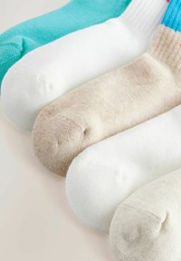 Five pairs of socks arranged in a row; colors include teal, white, beige, and varying textures with ribbed and smooth finishes.