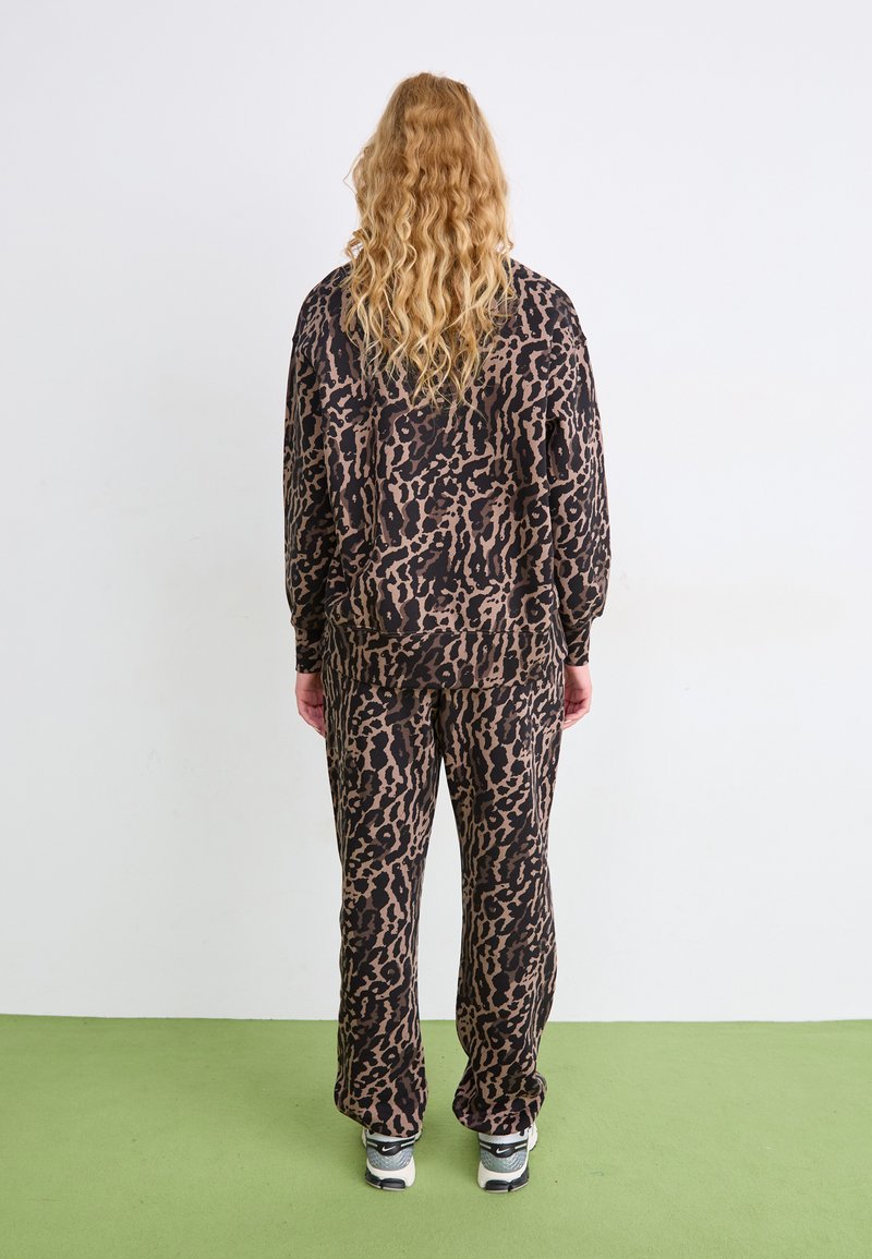 Sæt med leopardprintet loungewear i brun og sort, der har en løs pasform top og bukser. Blødt materiale, elastisk talje og sidelommer.