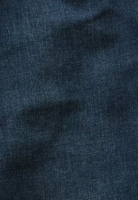 Tissu en denim bleu foncé avec un motif de tissage diagonal visible et des zones subtilement décolorées.