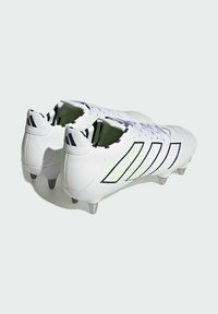 Botas de fútbol blancas con una textura suave, detalles en negro y verde neón, con un cierre de cordones en la parte delantera y seis tacos metálicos en la suela.